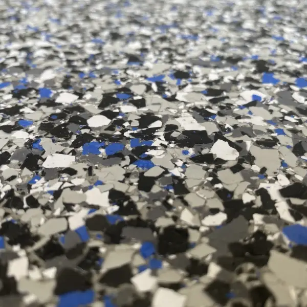 A textured surface featuring a mix of black, white, gray, and blue chips, resembling an abstract terrazzo floor pattern or speckled design.