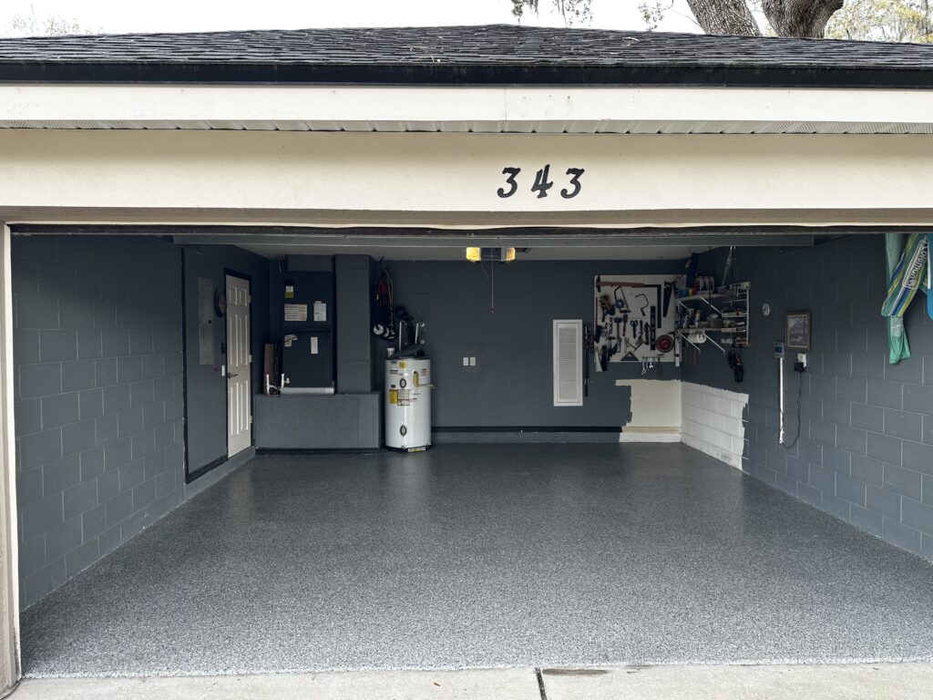 Empty garage with tools on the wall and a water heater. The floor is clean and the walls are painted gray. House number 343.